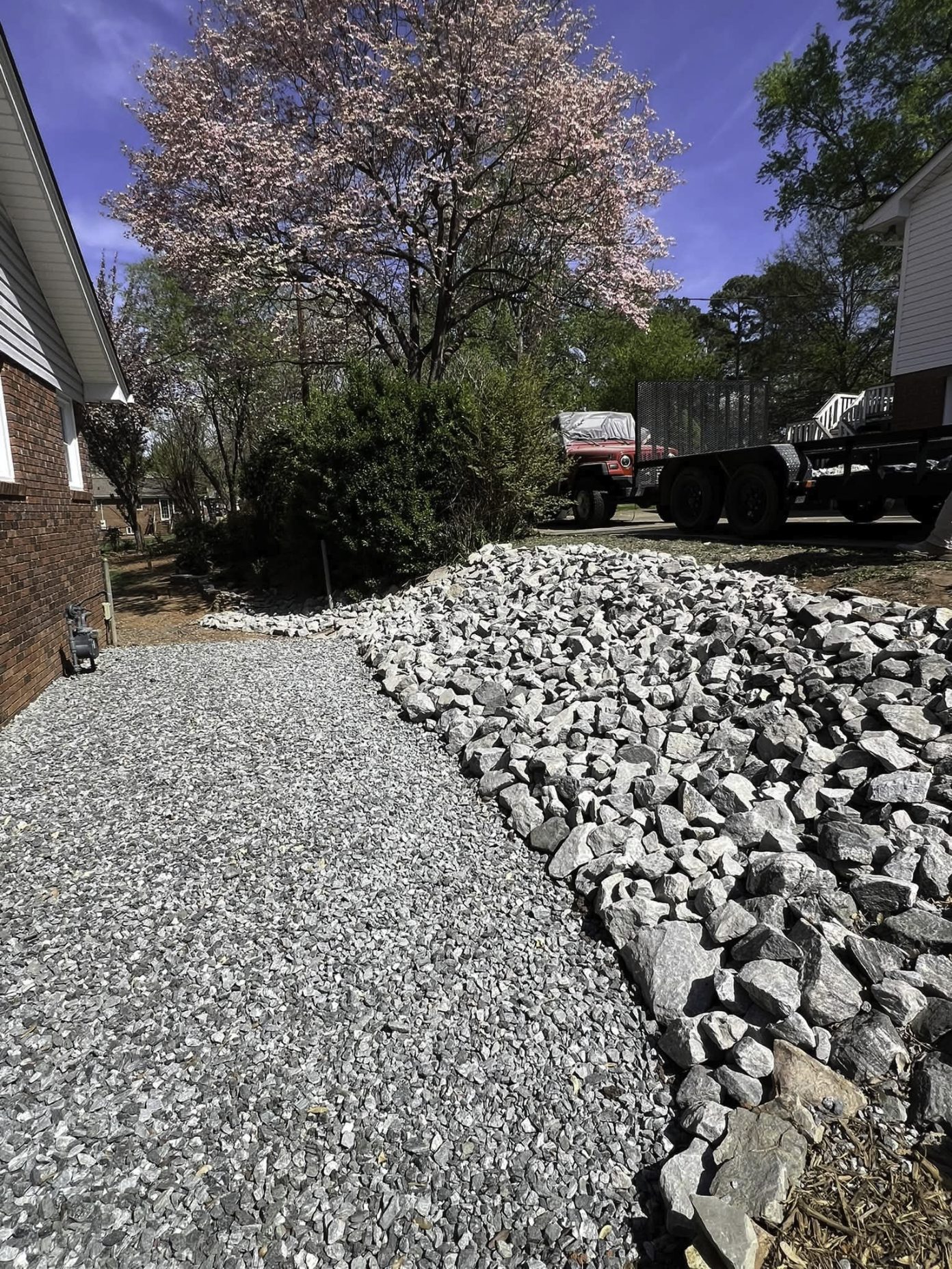 Large river rock drainage bed installed along a home's side yard